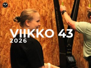 Kaksi aikuista tekee pariharjoitusta – toinen hiihtää, toinen kannustaa kahvakuulan vieressä